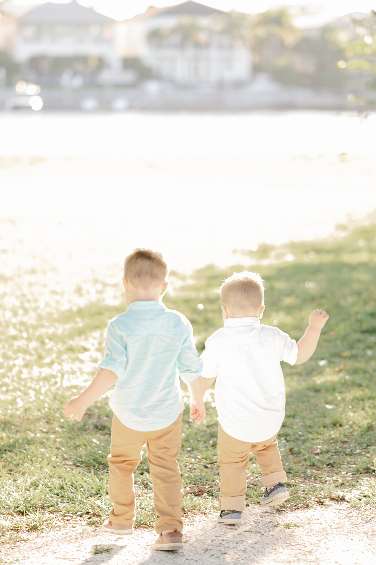 Two young brothers walk hand in hand toward the water in the golden light of a Chattahoochee Valley evening